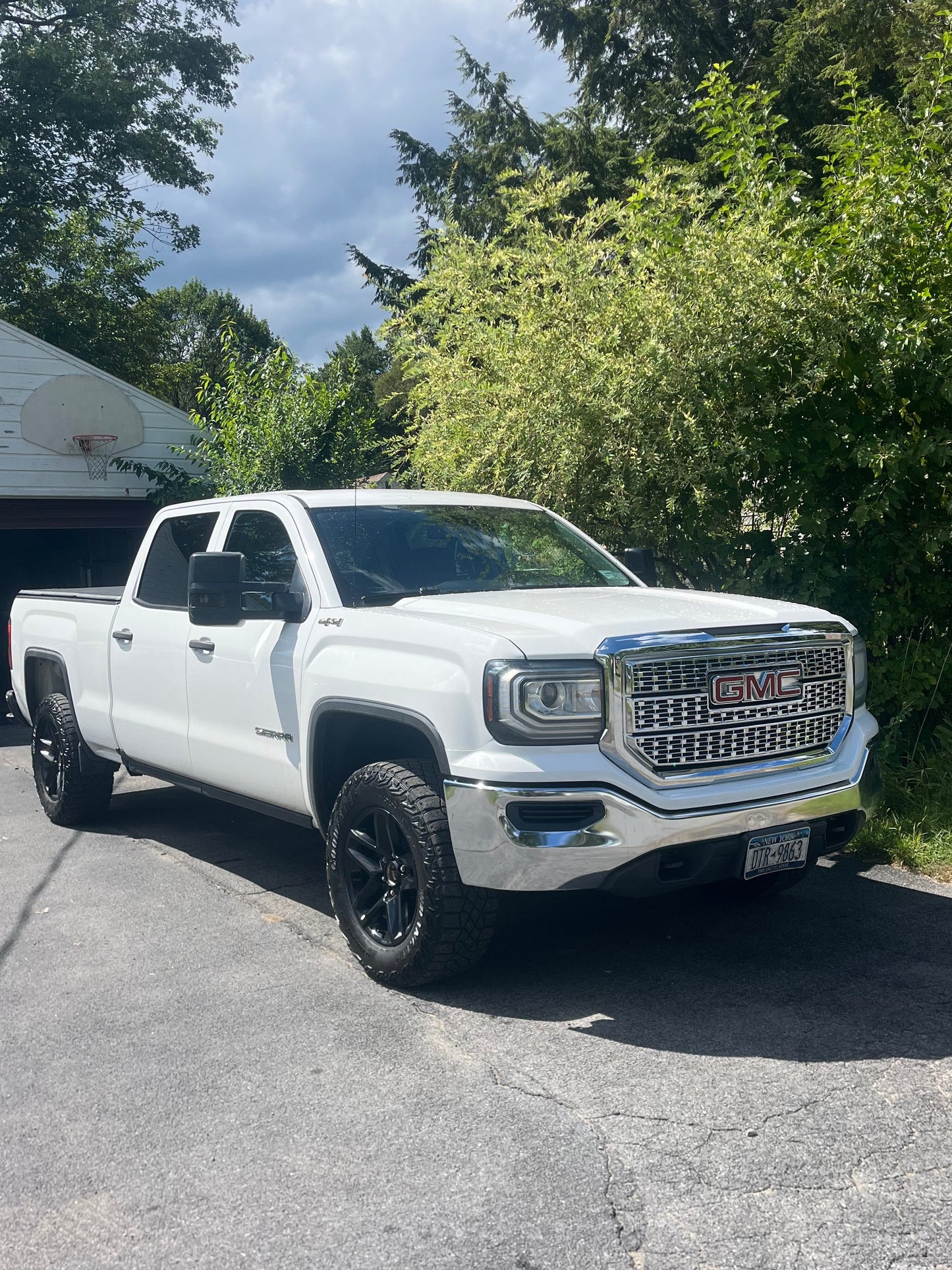 White truck parked on a driveway with trees in the background