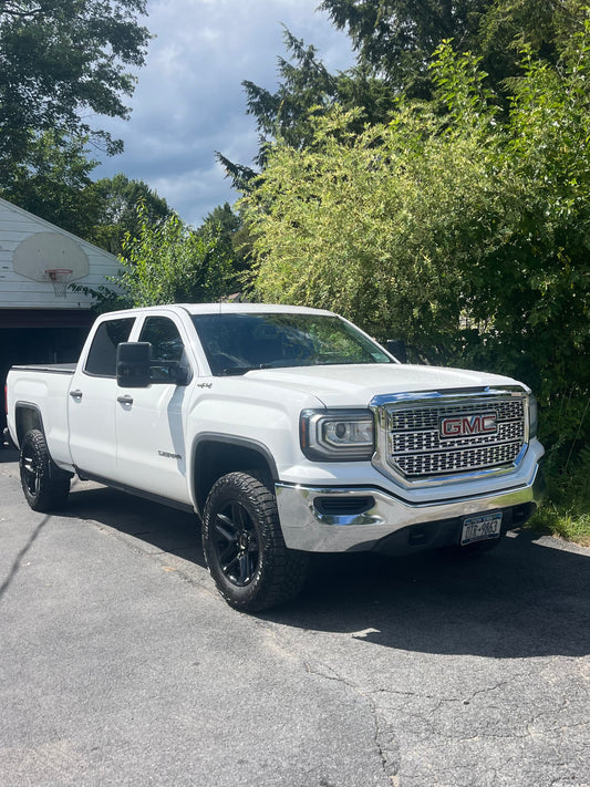 White truck parked on a driveway with trees in the background